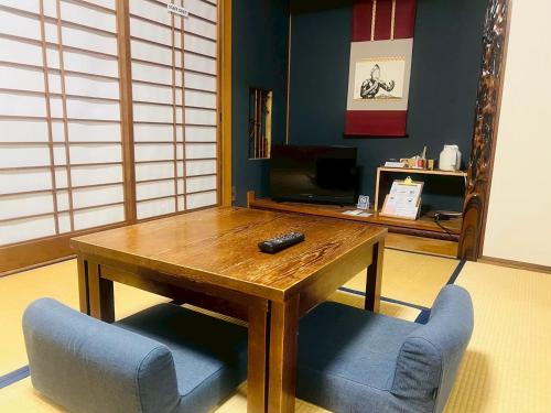 a living room with a wooden table and two blue chairs at Onomichi SINGAI HOSTELS in Onomichi