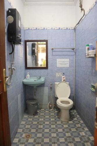 a blue tiled bathroom with a toilet and a sink at Rumah Panjaitan in Yogyakarta