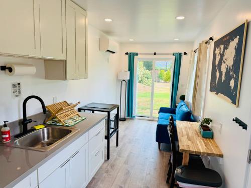 a kitchen and living room with a sink and a table at Hibiscus Hale - Perfect for 2! in Waialua