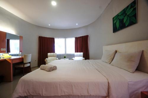 a bedroom with a large white bed and a desk at Buring Residence By TOS Malang in Samaan