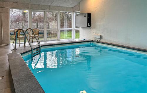 a swimming pool with two chairs in a building at Amazing Home In Ørsted With Sauna in Ørsted