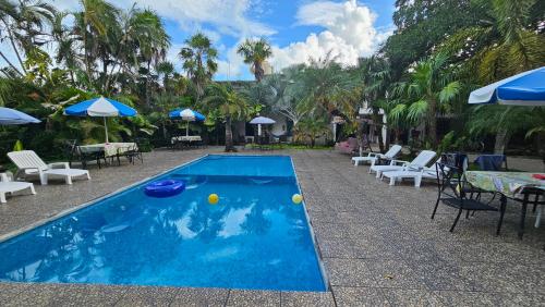 ein blauer Swimmingpool mit Liegestühlen und Sonnenschirmen in der Unterkunft Hotel Henry Bacalar in Bacalar