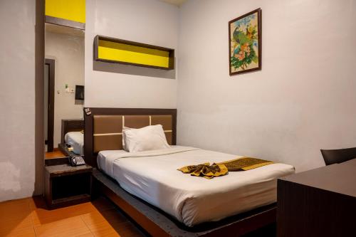 a hotel room with a bed with a towel on it at Tripletree Majestiq Hotel in Pekanbaru