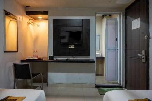 a room with a television on a wall with a table at Tripletree Majestiq Hotel in Pekanbaru