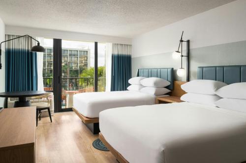a hotel room with two beds and a balcony at Sheraton Orlando Lake Buena Vista Resort in Orlando