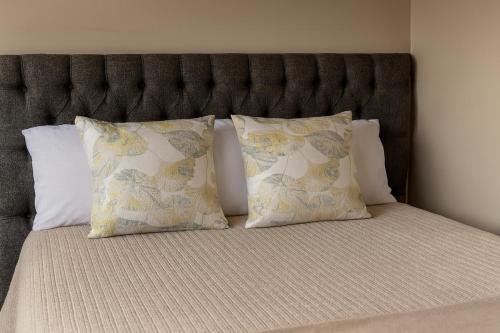 a bed with two pillows and a headboard at 12a Infinity Guesthouse in Pietermaritzburg