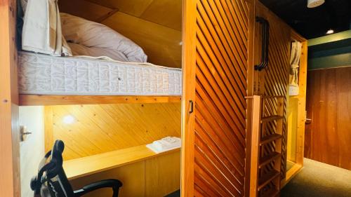 a small room with a bunk bed and a ladder at Onomichi SINGAI HOSTELS in Onomichi