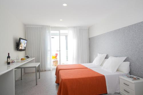 埃爾阿雷納爾的住宿－巴伊亞皇家酒店，一间卧室配有一张床和一张书桌及电视