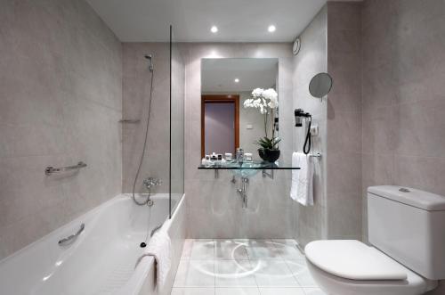 a bathroom with a tub and a toilet and a sink at Exe Zaragoza WTC in Zaragoza