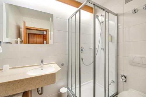 ein Bad mit einer Dusche und einem Waschbecken in der Unterkunft Business Class Hotel Häckermühle in Tiefenbronn