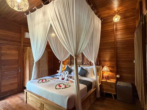 a bedroom with a canopy bed with white curtains at Villas Ume Sedani in Sidemen