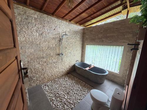 a bathroom with a bath tub and a toilet at Villas Ume Sedani in Sidemen