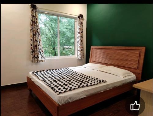 a bed in a green room with a window at Christa Homestay in Mangalore