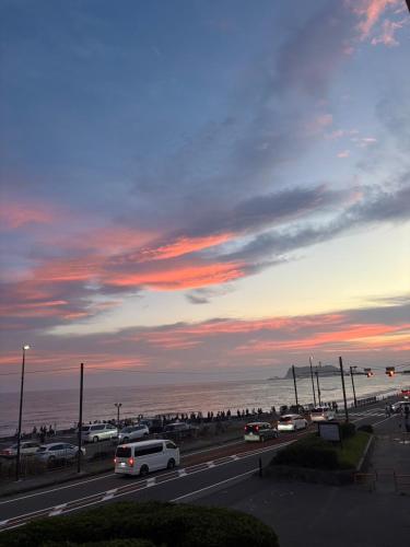 a road with cars parked on the beach at sunset at Hotel134 鎌倉 in Kamakura
