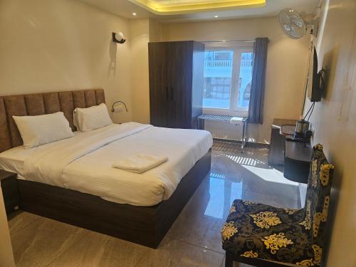 a bedroom with a bed and a chair and a window at Shahenshah Hotel in Civil Lines, Prayagraj in Prayagraj