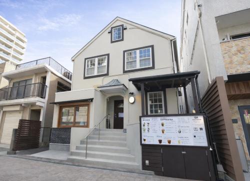 a white house with a sign in front of it at IZA Enoshima Guest House in Fujisawa