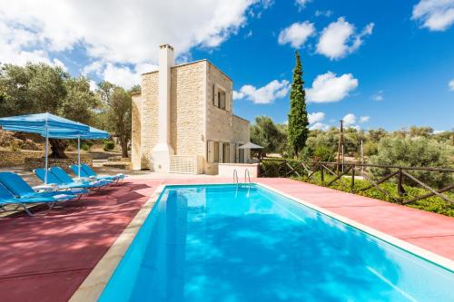 una piscina al aire libre con sillas y una villa en Maroulas Villa Estate en Maroulás