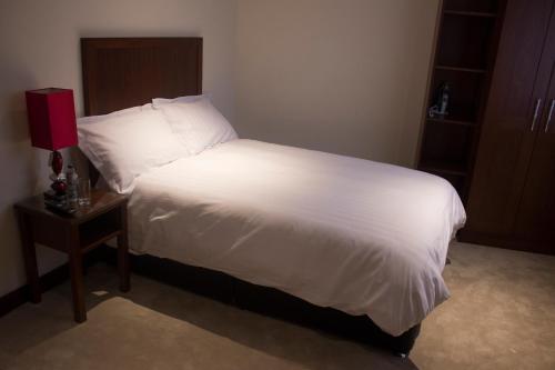 um quarto com uma cama com lençóis brancos e uma mesa em Beaumont House em Beaumont