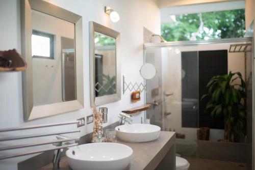 a bathroom with two sinks and two mirrors at Tamarindo Sunshine in Tamarindo