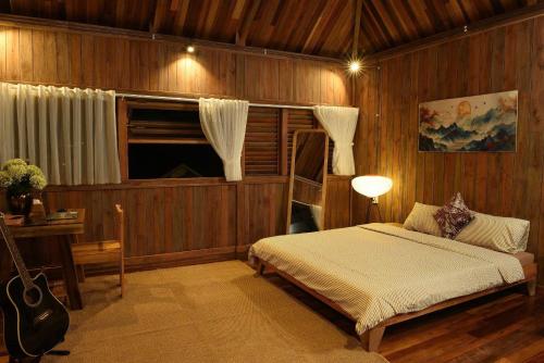 a bedroom with a bed and a guitar in it at Yugen Village in Khu Chi Lăng