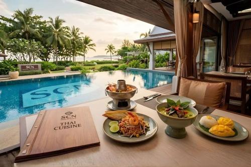 a table with food on it next to a swimming pool at SCN Wellness Spa & Resort Rayong in Ban Chang