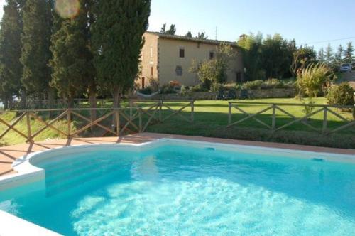 a large blue swimming pool in front of a house at Agriturismo Casanova in Asciano