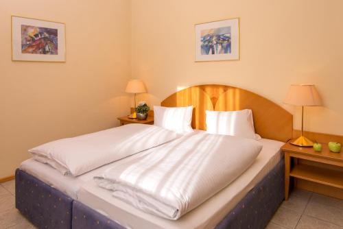 sypialnia z dużym łóżkiem z białą pościelą w obiekcie Hotel Stoiser Graz w Grazu