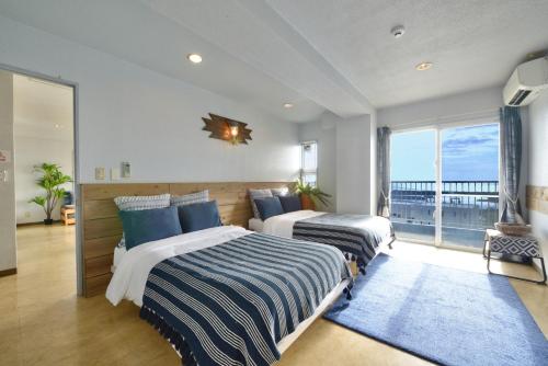 two beds in a bedroom with a view of the ocean at Sea Side TOYA in Yomitan