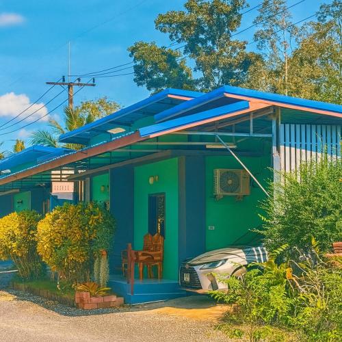 a blue and green house with a car parked in front at ใบตองรีสอร์ท in Ban Thung Kha Chomphu