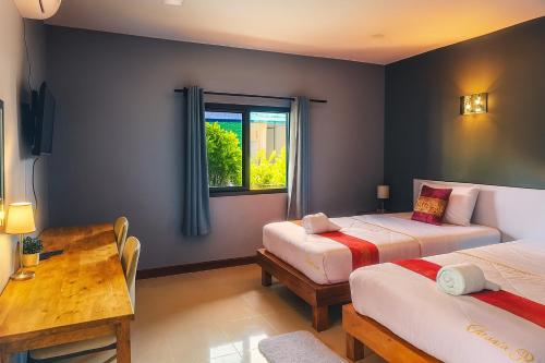 a bedroom with two beds and a table and a window at ใบตองรีสอร์ท in Ban Thung Kha Chomphu