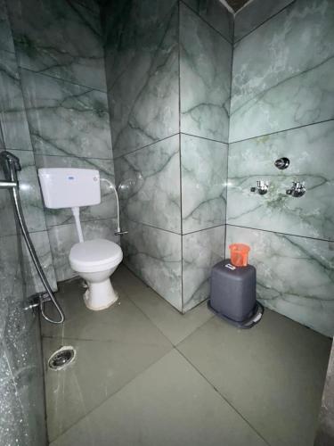 a bathroom with a toilet and a blue suitcase at Gajanand Homestay in Ujjain