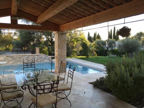a patio with a table and chairs and a swimming pool at Les 4 éléments in Tourrettes-sur-Loup