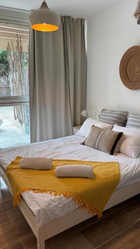 a bedroom with a large bed with a yellow blanket at The Beach Garden Apt. in Caesarea