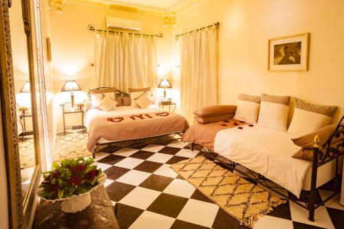 a bedroom with two beds and a checkered floor at Riad Dar Sofian in Zagora