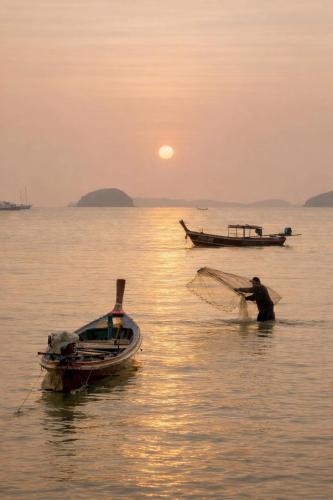 a man in the water with a net in the water at Fisherman Way Beach Villa in Rawai Beach
