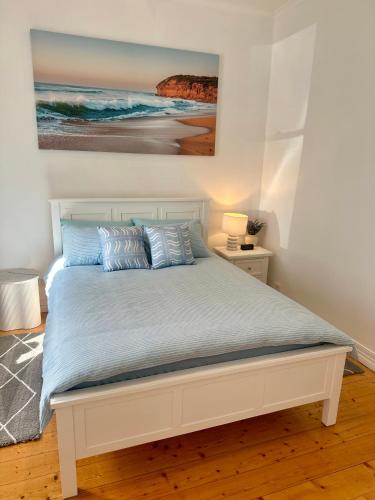 a bed in a bedroom with a painting on the wall at Botanical Gardens City Cottage in Geelong