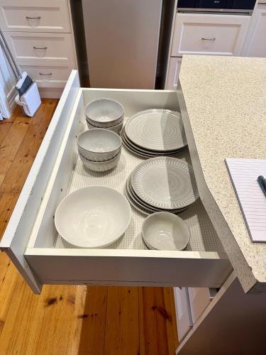 a drawer filled with white plates in a kitchen at Botanical Gardens City Cottage in Geelong