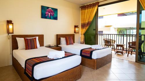 two beds in a hotel room with a balcony at Kata Silver Sand in Kata Beach