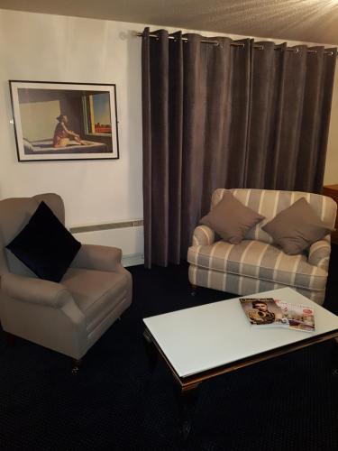 sala de estar con 2 sillas, sofá y mesa en Cohannon Inn, en Dungannon