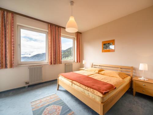 ein Schlafzimmer mit einem Bett und zwei Fenstern in der Unterkunft Cozy Apartment in Afritz am See near Gerlitzen Ski Area in Afritz