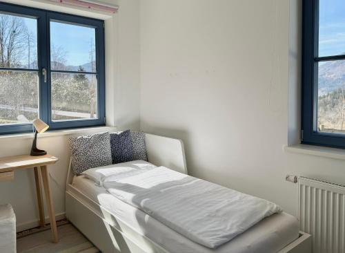 a white bed in a room with windows at Ein Haus am Berg in Marquartstein
