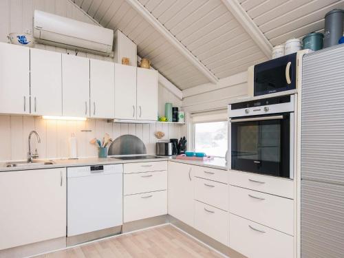 a kitchen with white cabinets and a microwave at 4 star holiday home in Vejers Strand in Vejers Strand