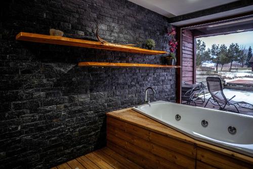 a bath tub in a room with a brick wall at Relax & Luxury apartment in Veľká Lomnica