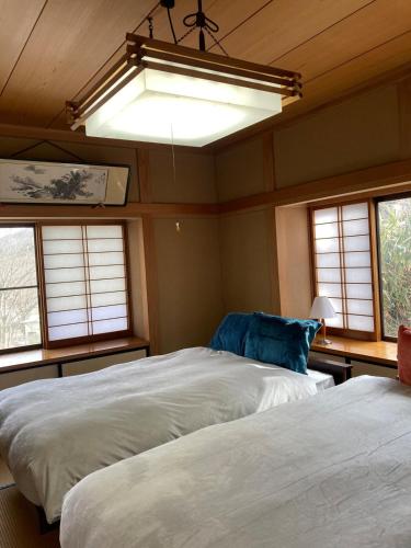 two beds in a room with windows and a light at 民泊ひなたぼっこ1日1組限定離れ貸切 in Nagano