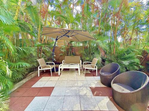 a patio with a table and chairs and an umbrella at Dou Cocon, Calme et Confort Moderne in Sainte-Clotilde