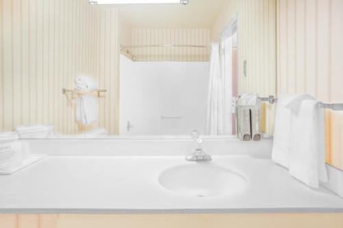 a white bathroom with a sink and a tub at Ramada by Wyndham Barstow in Barstow