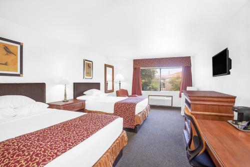 a hotel room with two beds and a television at Ramada by Wyndham Barstow in Barstow