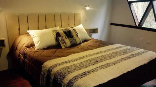 a bedroom with a bed with pillows and a window at Cuyinco Domos in Riñinahue