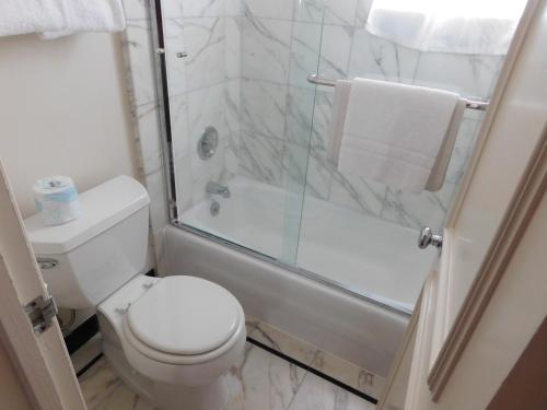 a bathroom with a toilet and a glass shower at Pine Inn - Carmel in Carmel