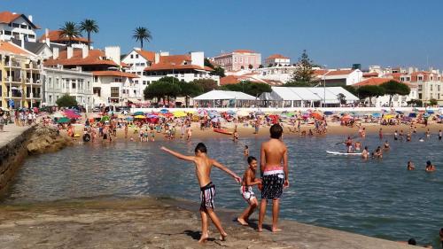 eine Gruppe von Menschen, die am Strand stehen in der Unterkunft Alojamentos Campo & Mar - T1 com Piscina in São Martinho do Porto